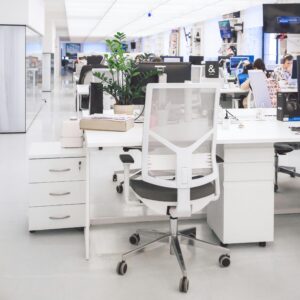 Bright modern office interior with desks, chairs, and computers in an open-plan workspace.